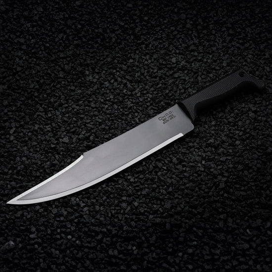 Okapi Bowie machete featuring Tactical Black handle shown on black stone ground