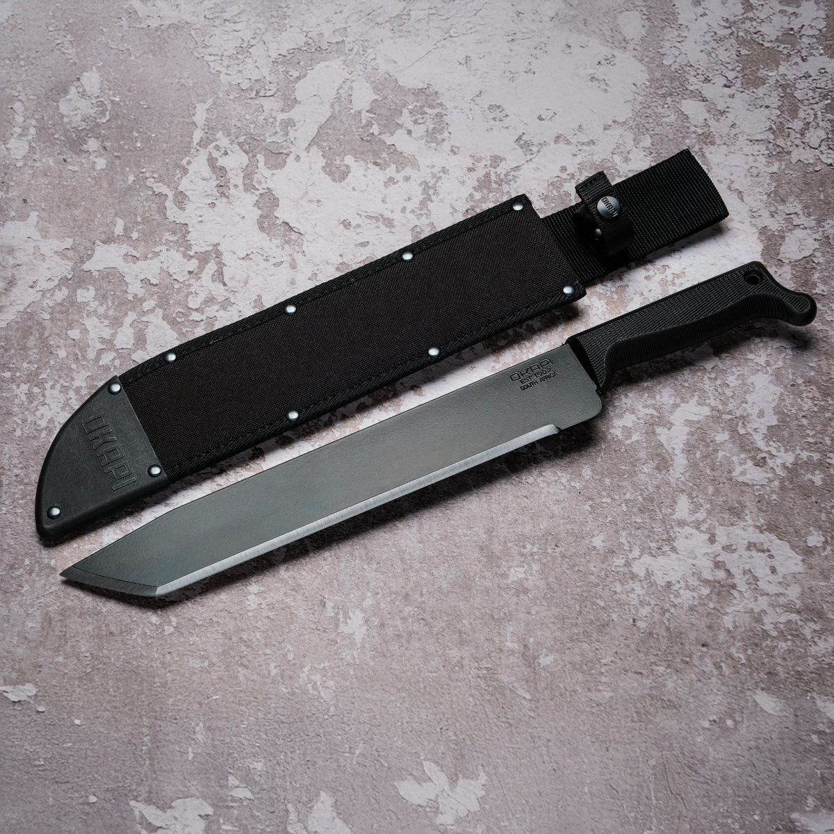 Okapi O-Tanto Machete with black handle with black Sheath on grey background