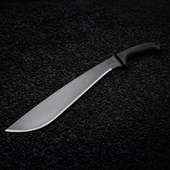 Tactical Okapi Jungle machete resting on black rock floor in lifestyle scene