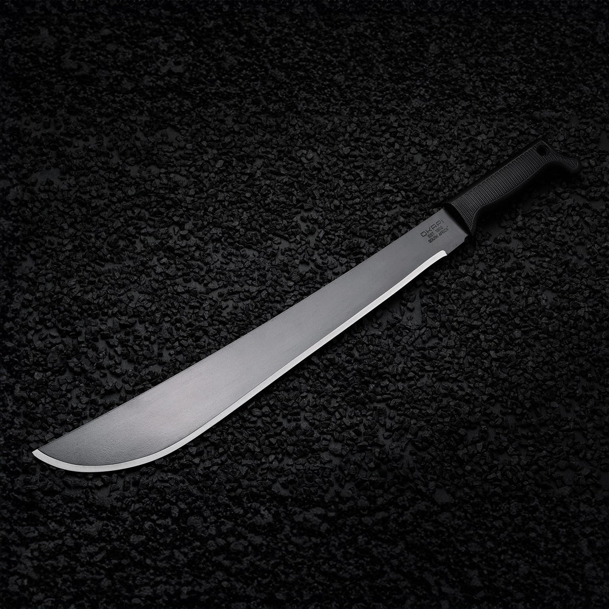 Black-handled Okapi Latin machete placed on rugged rock environment