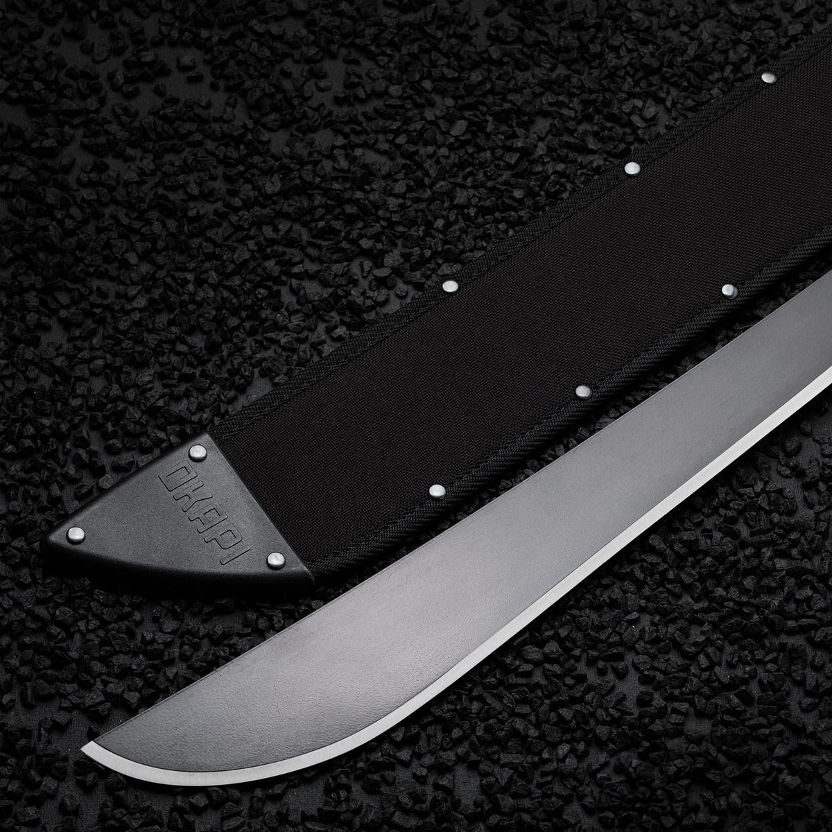 Okapi Latin-style machete with black handle and sheath displayed outdoors