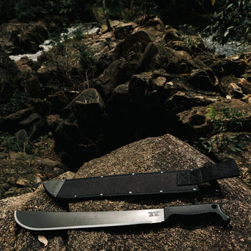 Latin machete by Okapi in sheath with rugged black handle shown in outdoor scene