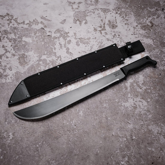 Okapi Latin machete with black tactical handle and sheath in outdoor setting