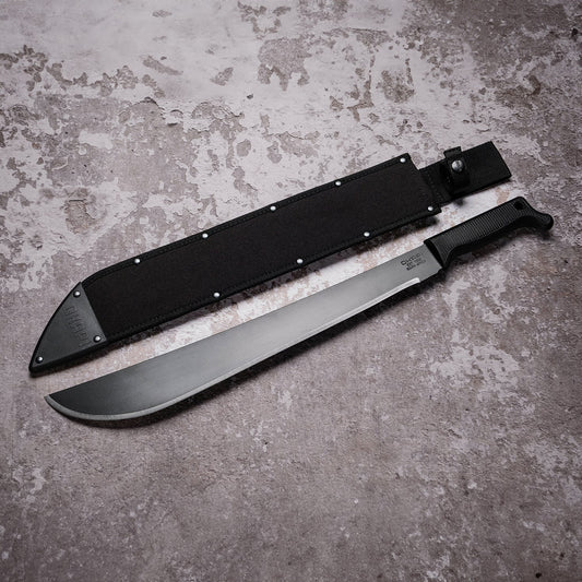 Okapi Latin machete with black tactical handle and sheath in outdoor setting