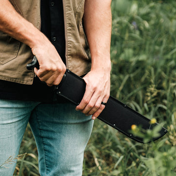 Okapi O-Tanto machete with black tactical handle and sheath in outdoor setting