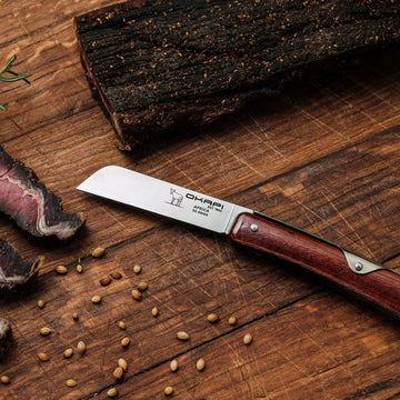 Close-up Okapi Biltong Knife opened up on wooden background with biltong