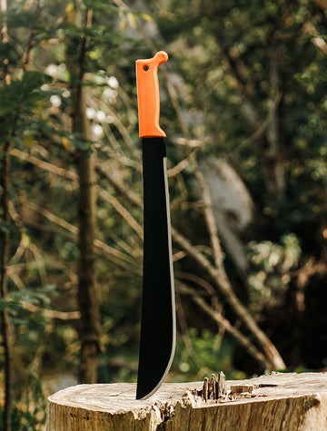 Okapi Latin machete positioned in wilderness scene, Okapi Orange handle visible