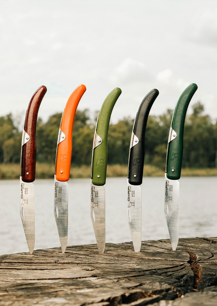 Okapi Pocket knife collection with a variety of handles with waterfront background